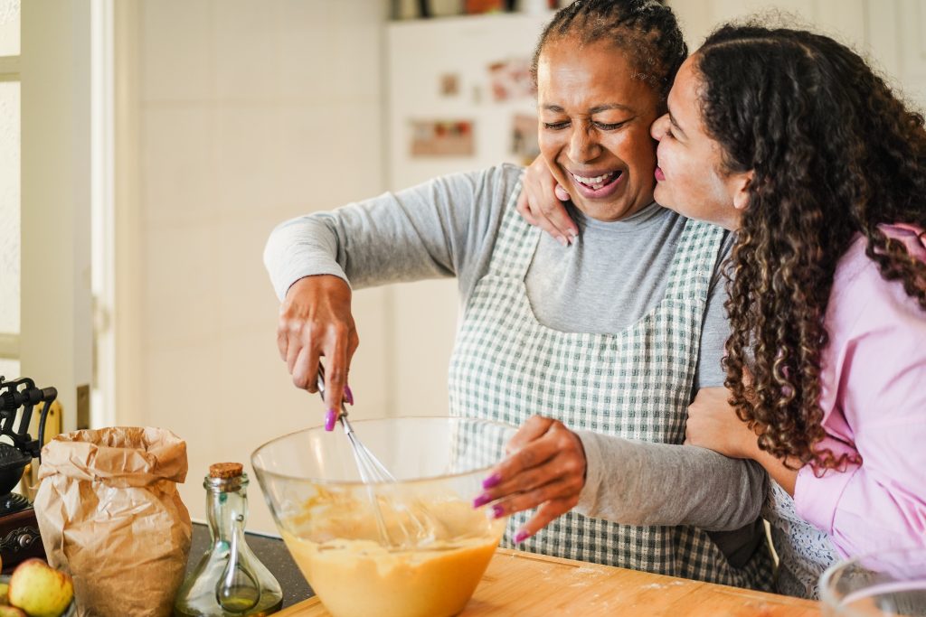 Mother and daughter having fun preparing cake at home - Family lifestyle and cooking healthy food concept - Focus on mum's face
