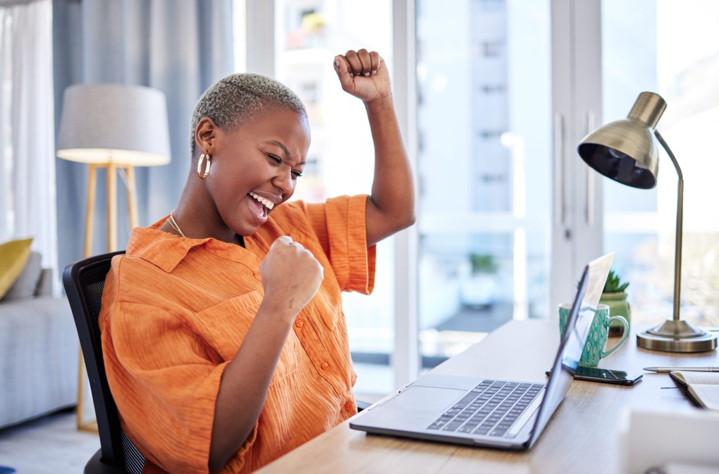 Businesswoman, laptop or winner with fist pump for winning, success or promotion bonus in home office. Happy black woman trader trading or cheering with prize, goal target or good news in remote work.