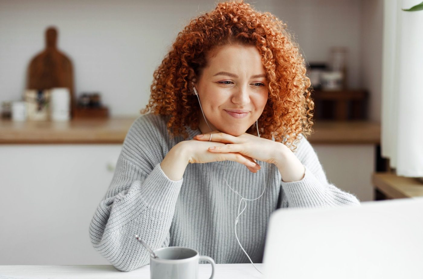 Smiling woman using laptop at her kitchen table